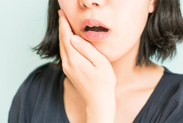 口を開けて頬に手を当てている女性